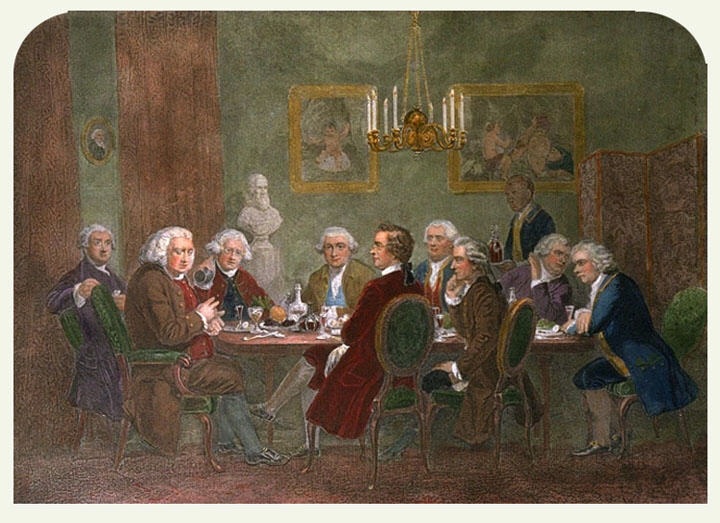 Dining room with nine men seated around a table. The dinner has been finished, and a large man at the head talks and gesticulates while the others eagerly listen. The men wear wigs and clothing of late 18th century Britain, and the furniture, hangings, and chandelier are of similar vintage. A liveried servant is entering with a tray bearing two high-shouldered decanters of wine.